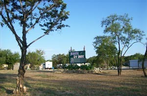 The Jurassic RV Park sign by the road, with trees and open grass